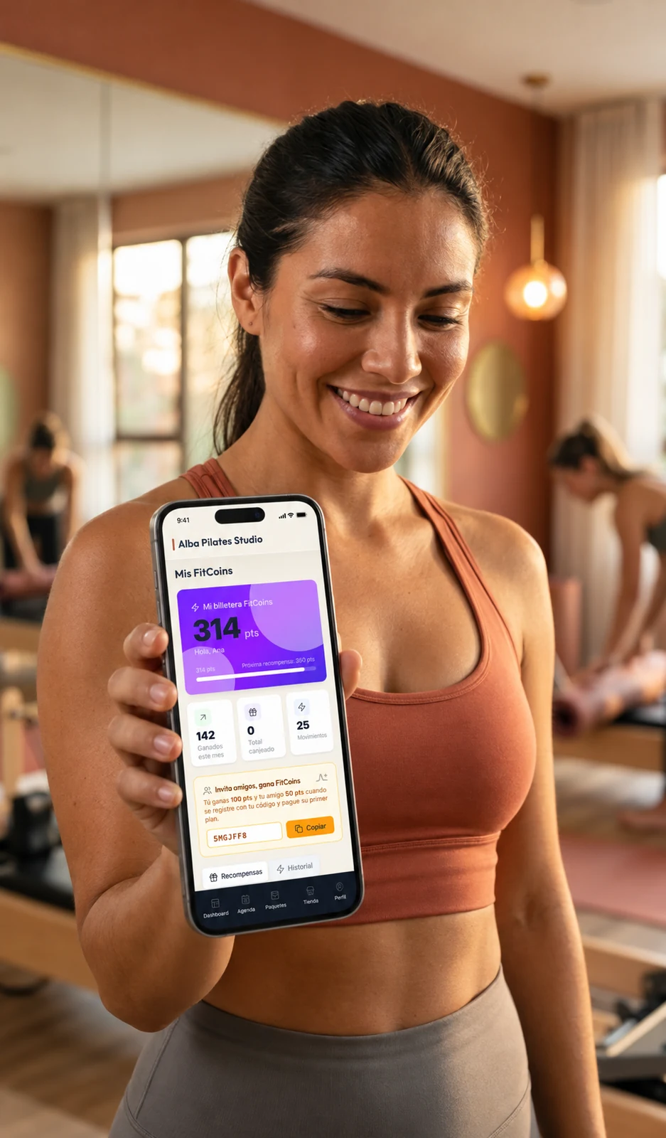 Alumna mostrando la pantalla real de FitCoins de Alba Pilates Studio en su celular